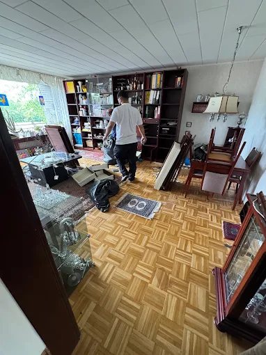 Mitarbeiter von Robins räumt ein Wohnzimmer mit Regalen und Vitrinen