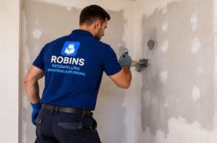 Mitarbeiter von Robins spachtelt eine Wand